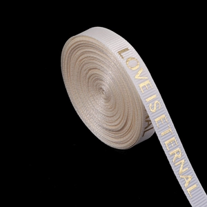 Detail of cream ribbed ribbon with gold foil text Love is Eternal on black background