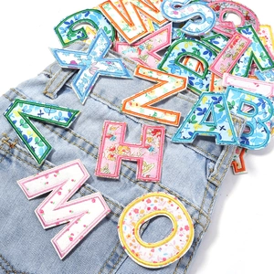Close-up of floral embroidery patches on denim showing 26 English alphabet letters