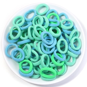 Macro shot of blue and green elastic hair bands in soft ribbed fabric on a white dish
