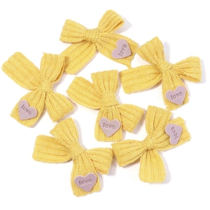 Sechs gelbe gestrickte Schleifen mit lila Herz-Love-Anhängern auf weißem Hintergrund