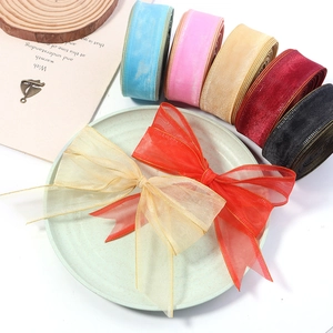 Macro view of organza ribbons with gold edges and handmade DIY bows on a tray
