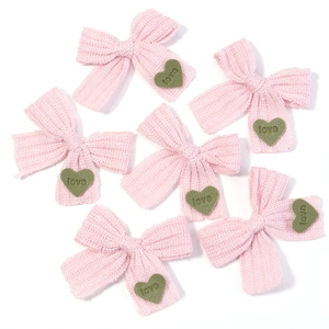 Detailansicht von rosa Strickschleifen mit grünen Herz-Patches für DIY-Zubehör