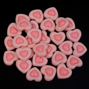 Macro shot of two-tone pink resin heart charms for DIY crafts and jewelry making