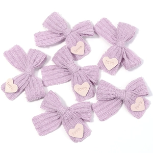Detail von lila gestrickten Schleifen mit weißen Liebesherz-Patches für DIY-Basteln