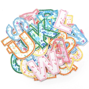Detailed view of floral embroidery alphabet patches with colorful stitched edges for DIY