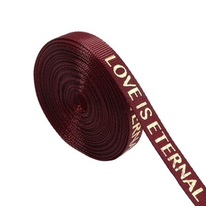 Macro shot of burgundy ribbed ribbon with gold foil LOVE IS ETERNAL text for gift wrapping