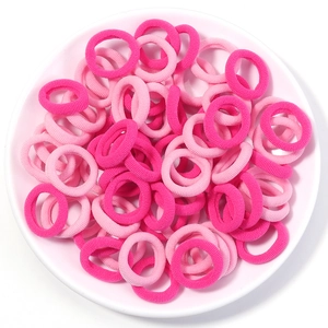 Close-up of assorted pink seamless elastic hair bands for children in a white bowl