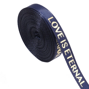 Macro view of dark blue ribbed ribbon with gold LOVE IS ETERNAL lettering for gift wrapping
