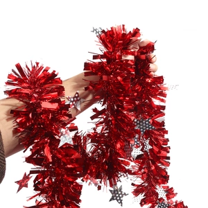 Detail of red metallic Christmas tinsel with silver star sequins held by a hand