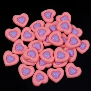 Macro shot of dual-tone pink and purple resin heart cabochons for DIY crafts