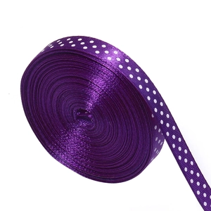 Detailed close-up of a deep purple polyester satin ribbon roll with white polka dots