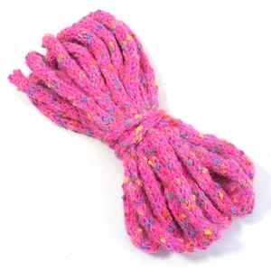 Detail of rose pink speckled yarn roll with multicolored dots and cable knit texture