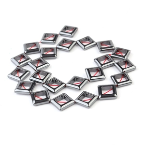 Macro detail of dark grey hematite square spacer beads strung on a red cord