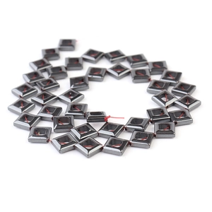 Macro detail of square hematite beads with metallic luster on red cord for jewelry making