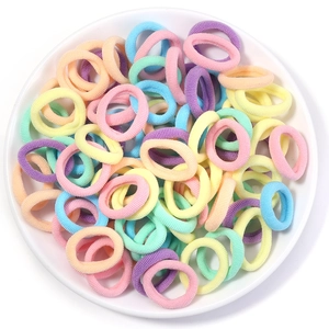 Macro view of assorted pastel high-elastic hair ties in a white ceramic dish