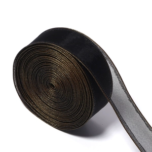 Detail of black organza ribbon with golden satin edges for luxury gift wrapping and DIY crafts