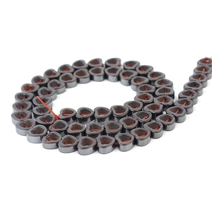 Macro shot of heart-shaped hematite loose beads with dark grey metallic luster for DIY jewelry