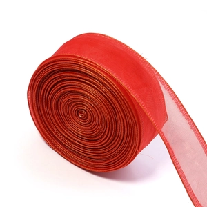 Macro detail of red sheer organza ribbon with gold metallic edge trim on a roll