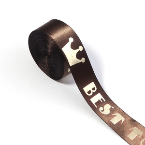 Detailed macro view of dark brown satin ribbon with gold crown and BEST lettering