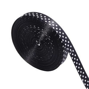 Close-up of black polyester ribbon roll with white polka dots for gift packaging