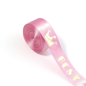 Close-up of pink satin ribbon with gold crown and BEST lettering for gift wrapping