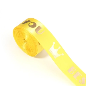 Detail of yellow satin ribbon with golden crown and letter prints for gift wrapping