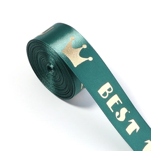 Detail of dark green satin ribbon with gold crown and BEST lettering for gift wrapping