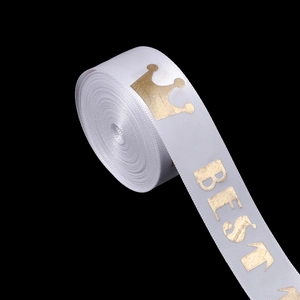 Close-up of white satin ribbon with golden crown and BEST letter print for gift wrapping