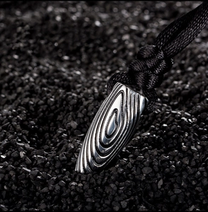 Gros plan sur pendentif balle en acier inoxydable poli avec texture gravée unique