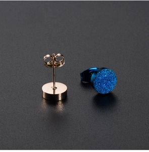 Vista macro de pendientes de oro rosa con cristales azules brillantes y cierre mariposa