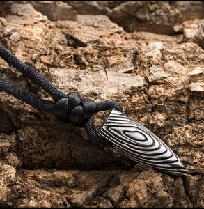 Vue macro d'un pendentif balle en acier titane avec des textures ondulées concentriques