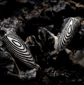 Gros plan de pendentifs balle en titane avec texture ondulée sur pierre naturelle humide
