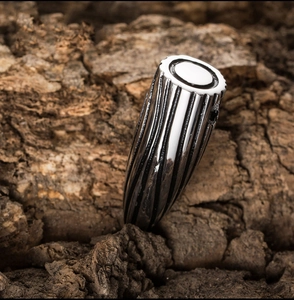 Vue détaillée d'un pendentif balle en acier inoxydable texturé sur un fond de bois