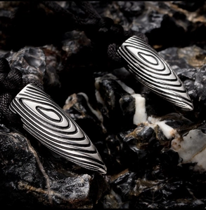 Macro de pendentifs balles en acier argenté avec texture bois sur roche volcanique