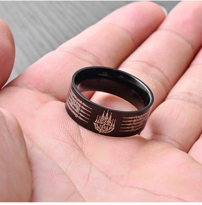 Detalle de anillo de acero de titanio negro con grabados de escrituras tailandesas doradas