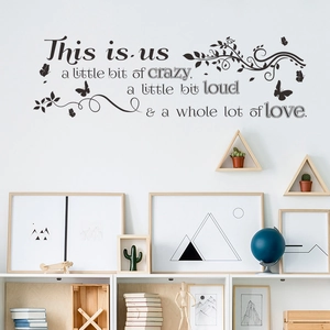 Dettaglio adesivo murale farfalla e vite con scritta 'This is us' in un ambiente di casa