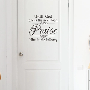 Detail of black vinyl wall sticker with religious text on a white wooden interior door