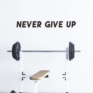 Détail de l'autocollant Never Give Up derrière le banc de musculation et l'haltère