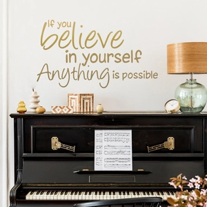 Detail of inspirational vinyl wall decal on white wall above a black piano and decor