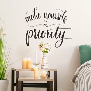 Macro shot of 'make yourself a priority' vinyl wall decal on a clean white wall
