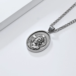 Détail du pendentif ovale avec relief de Jésus sur une chaîne tressée en métal argenté