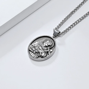 Détail macro du pendentif ovale Saint François sur une chaîne en acier tressé