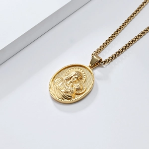 Détail d'un pendentif relief ovale doré avec une chaîne à mailles blé sur fond blanc