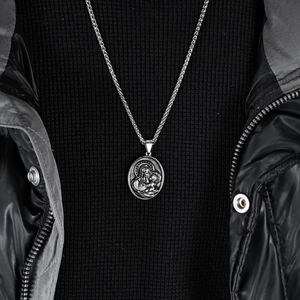 Collier vintage argenté avec pendentif Vierge Marie et chaîne blé sur pull foncé