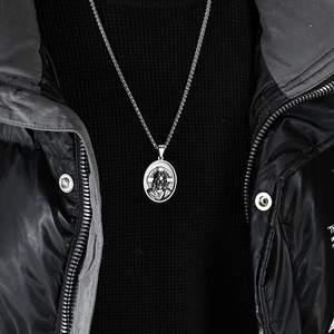 Gros plan d'un collier pendentif Jésus ovale en argent porté sur un pull sans manches noir
