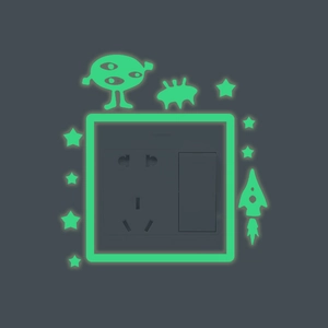 Luminous rocket and alien wall stickers glowing around a light switch in the dark