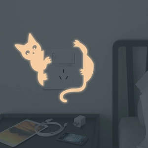 Luminous cat-shaped light switch wall sticker showing warm yellow glow in a dark bedroom