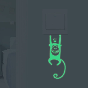 Luminous green monkey wall sticker glowing in dark near home light switch plate
