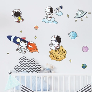 Detail of cartoon astronaut and rocket wall stickers in a cozy nursery room setting