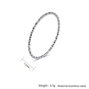 Detalle de anillo fino de 1,2mm en acero inoxidable con textura de diamante y peso de 0,5g